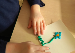 Zabawy z plasteliną - dziecko wykleja wiosenny kwiat.