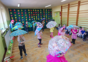 Dzieci tańczą z parasolami do piosenki, pt.: "Kiedy pada deszcz".