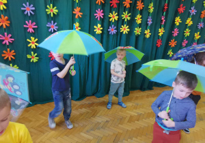 Dzieci tańczą z parasolami do piosenki, pt.: "Kiedy pada deszcz".