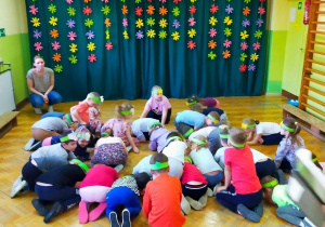 Dzieci klęczą podczas zabawy muzycznej.