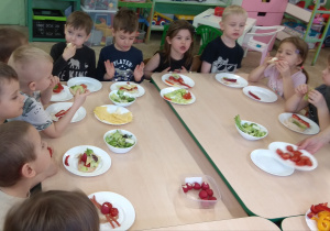 Dzieci jedzą przygotowane samodzielnie kanapki.