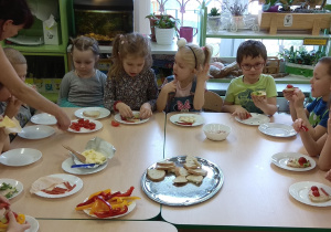 Dzieci jedzą samodzielnie przygotowane kanapki.