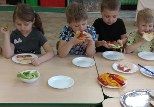 Dzieci jedzą samodzielnie przygotowane kanapki.