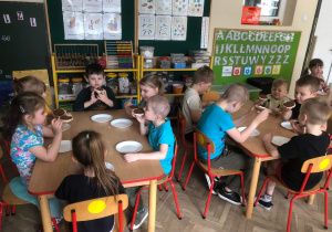 Dzieci siedzą przy stole podczas jedzenia kanapki z własnoręcznie wykonaną zdrową nutellą.