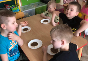 Dzieci siedzą przy stole podczas jedzenia kanapki z własnoręcznie wykonaną zdrową nutellą.
