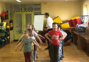 Dzieci stoją parami, wykonując układ taneczny.