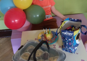 Chłopiec sieci przy stoliku, na którym czeka torcik - jabłuszko z 5 świeczkami, pyszne babeczki i cukierasy.