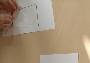 Dzieci wyklejają własne wzory na szablonach kubków.