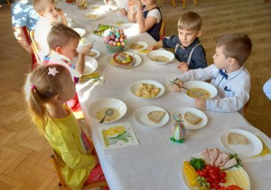 Dzieci spożywają potrawy przy wielkanocnym stole