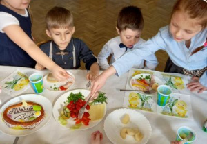 Dzieci spożywają potrawy przy wielkanocnym stole