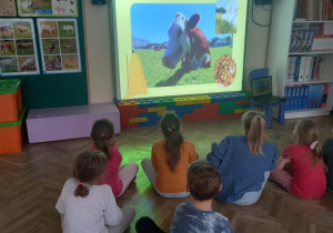 Dzieci siedzą i oglądają film edukacyjny.