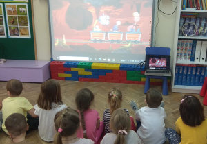 Dzieci oglądają na tablicy multimedialnej film edukacyjny o mrówkach.