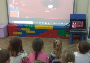 Dzieci oglądają na tablicy multimedialnej film edukacyjny o mrówkach.