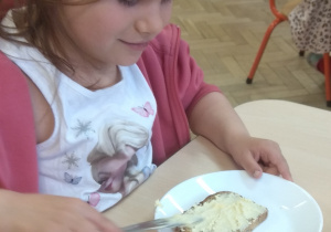 Dziewczynka smaruje pieczywo masłem.