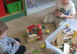 Chłopcy budują zamek z drewnianych klocków.