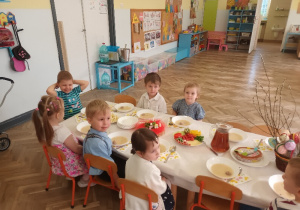 Dzieci siedzą przy Śniadaniu Wielkanocnym.