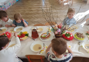 Dzieci delektują się białym barszczem z kiełbasą i jajkiem.