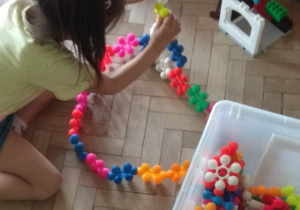 Dziewczynka buduje z klocków w kształcie kwiatów.