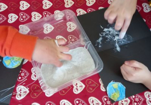 Dzieci nakładają farbę mydlaną na palec, a następnie na karton.