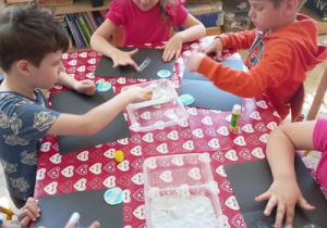 Dzieci nakładają palcami farbę mydlaną na kartony.