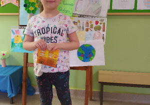 Dziewczynka trzyma nagrodę z przeglądu o ekologi.