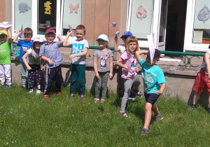 Dzieci puszczają swoje samoloty w ogrodzie przedszkolnym.