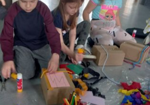 Dzieci ozdabiają kartonowe pudełka.