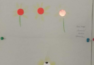Wystawa prac dzieci przedstawiająca przeistoczenie kropki w: kwiaty i domek.