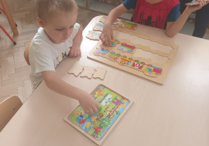 Chłopiec układa drewnianą układankę- wagoniki od 0 do 10.