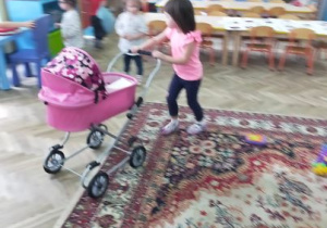 Dziewczynka prowadzi wózek dla lalek.