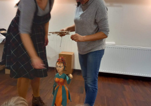 Pani prowadząca warsztaty pokazuje nauczycielowi w jaki sposób poruszać marionetką.