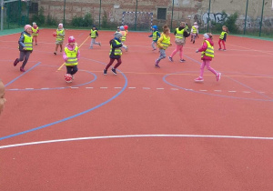 Dzieci biegają po boisku uciekając przed zbijającym je miękkimi piłkami berkiem.