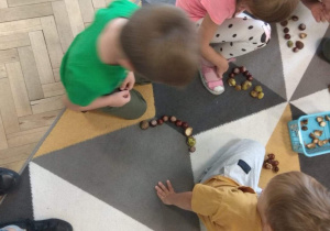 Dzieci tworzą różne kształty z kasztanów.