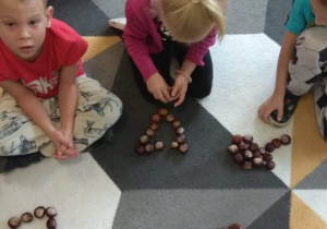 Dzieci tworzą różne kształty z kasztanów.
