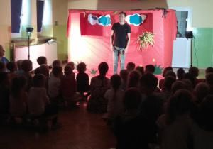 Aktor zaprasza dzieci na przedstawienie.