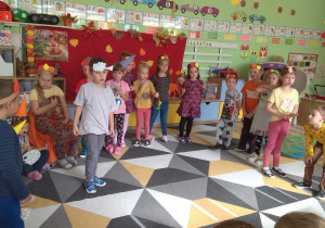 Dzieci wcielając się w swoje role występują na tle jesiennej dekoracji, przed kolegami i koleżankami z innej grupy.