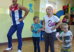 Troje dzieci wraz z instruktorem, pokazują taneczne pozy.