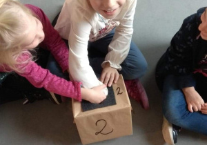 Dzieci próbują rozpoznać za pomocą dotyku, co jest ukryte w pudełku.