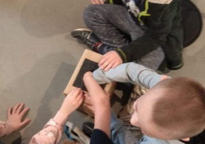 Dzieci próbują rozpoznać za pomocą dotyku, co jest ukryte w pudełku.