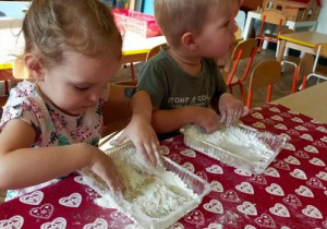 Dzieci dotykają rękoma mąkę.
