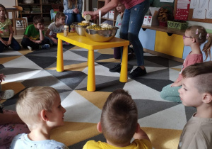 Dzieci siedzą w kole. Nauczyciel dodaje majonez do sałatki.