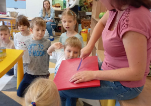 Nauczyciel pokazuje dzieciom, w jaki sposób używać noża w czasie krojenia warzyw.