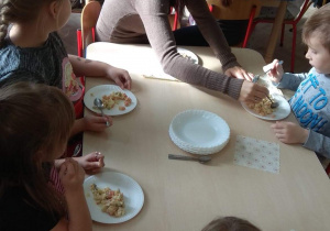 Dzieci i rodzice wspólnie degustują sałatkę.