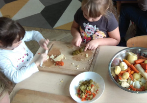 Dziewczynki kroją warzywa.