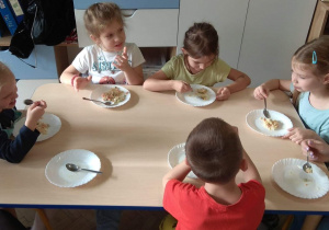Dzieci wraz z rodzicami jedzą sałatkę.