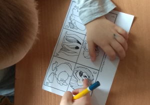 Chłopiec wskazuje na rysunku głowę lwa.