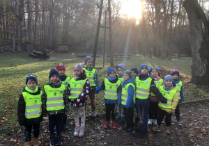 Dzieci stoją na tle lasu.