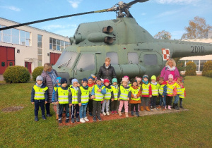 Dzieci stoją przy śmigłowcu wojskowym.