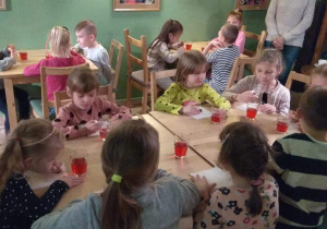 Dzieci jedzą ciasteczka i piją soczek.