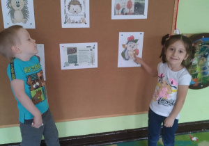 Dzieci stoją przy tablicy i pokazują wygląd jeża.